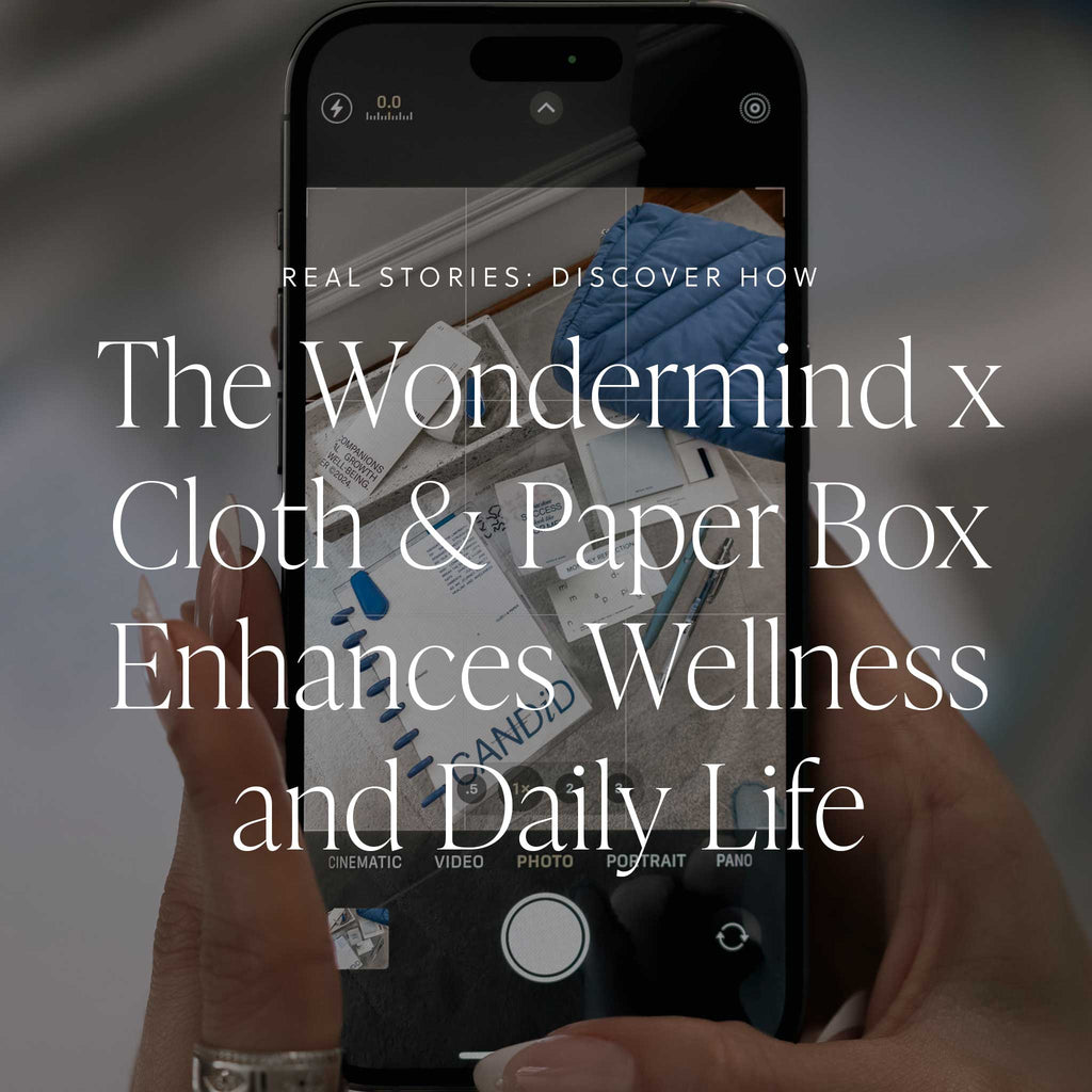 A photo of a mobile phone capturing the contents of the October Box, featuring a text overlay that says, "Real Stories: Discover How the Wondermind x Cloth & Paper Box Enhances Wellness and Dailly Life."