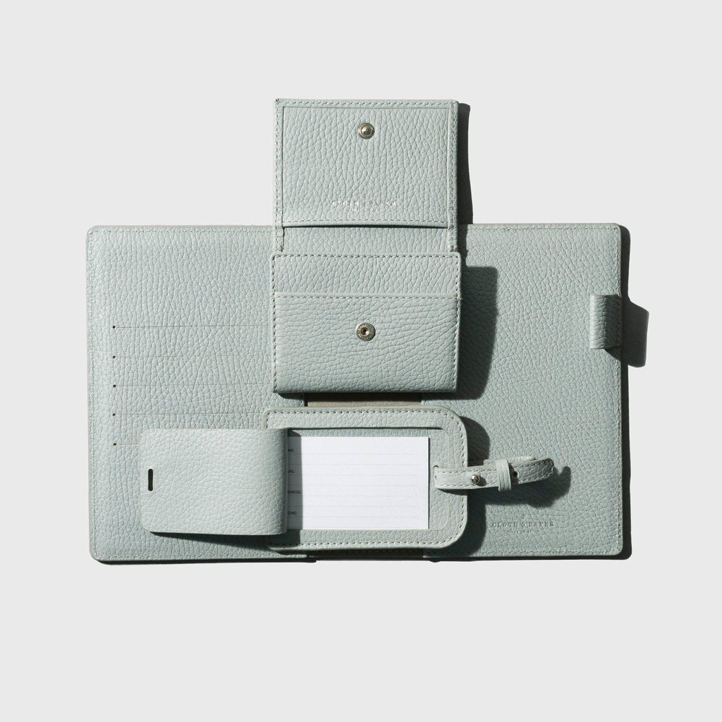 Folio, wallet, and luggage tag displayed on a neutral background. The folio, wallet, and luggage tag are all opened.