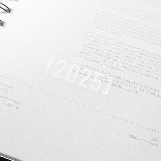 Closeup of screenprinted white [2025] on the notebook's clear cover, with cover page visible underneath.