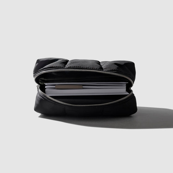 Pouch displayed open with notebooks inside it on a neutral background.