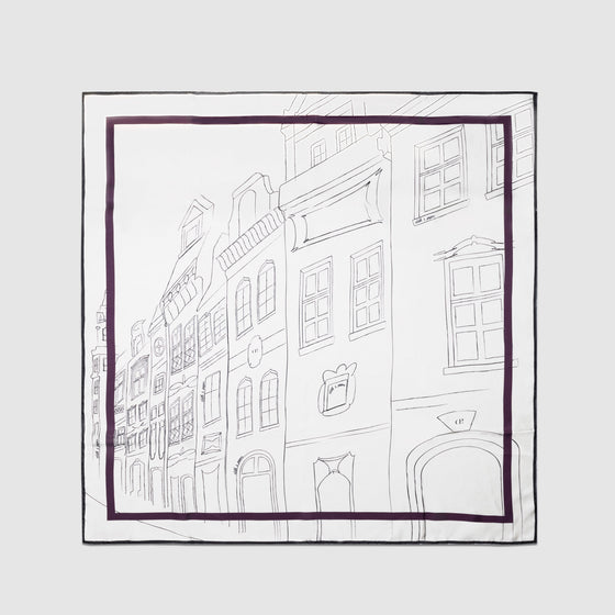 Silk Scarf, Pueblo, Cloth and Paper. Scarf displayed on a neutral background. It features a hand-drawn pattern with buildings and purple accents.