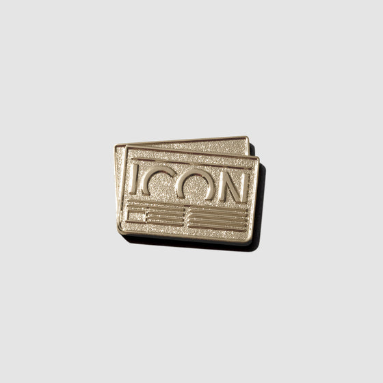 Gold pin displayed on a neutral background. Pin is shaped like a credit card with text reading "ICON" inside of it.