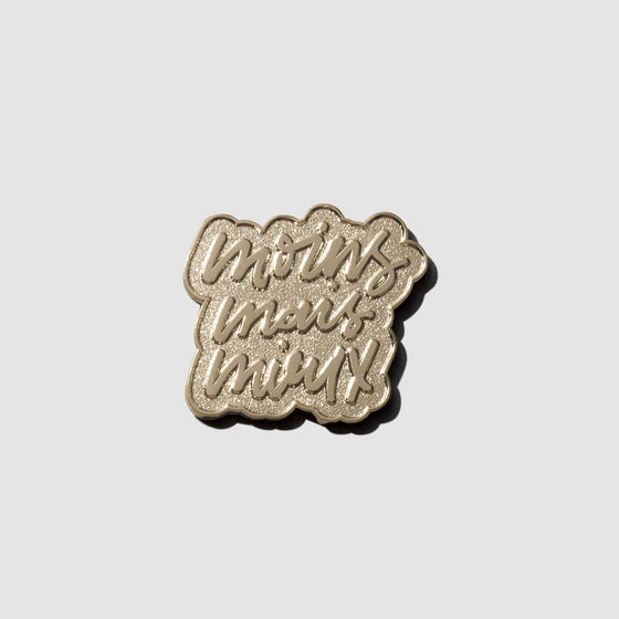 Gold pin displayed on a neutral background. Pin is handwritten text reading "moins mais mieux"