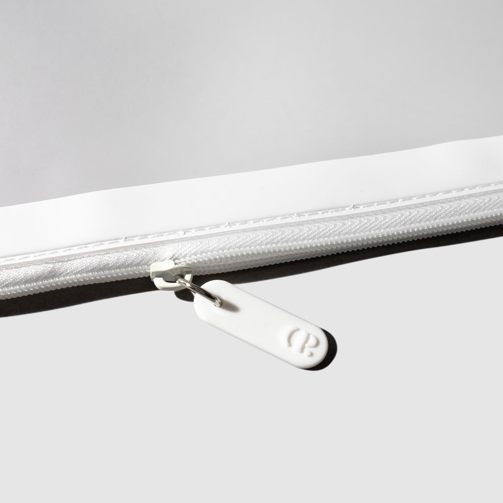 Closeup of white zipper detailing on bag.