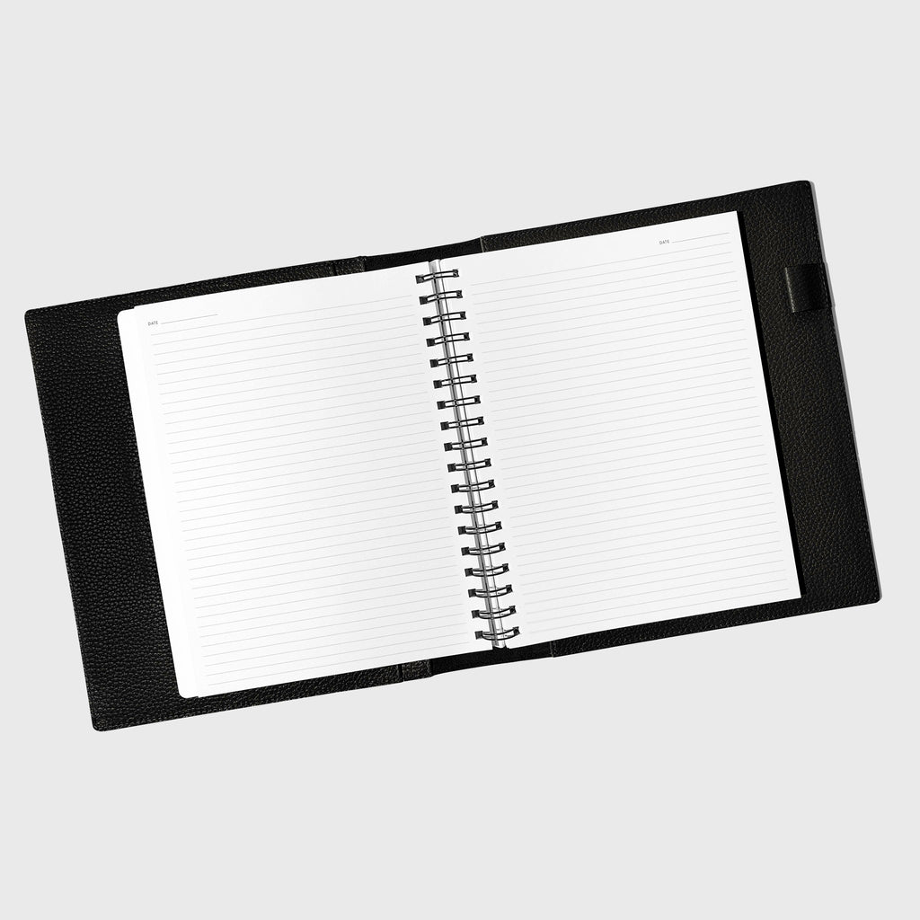 Notebook spread open inside a black leather agenda. Design shown is graph.