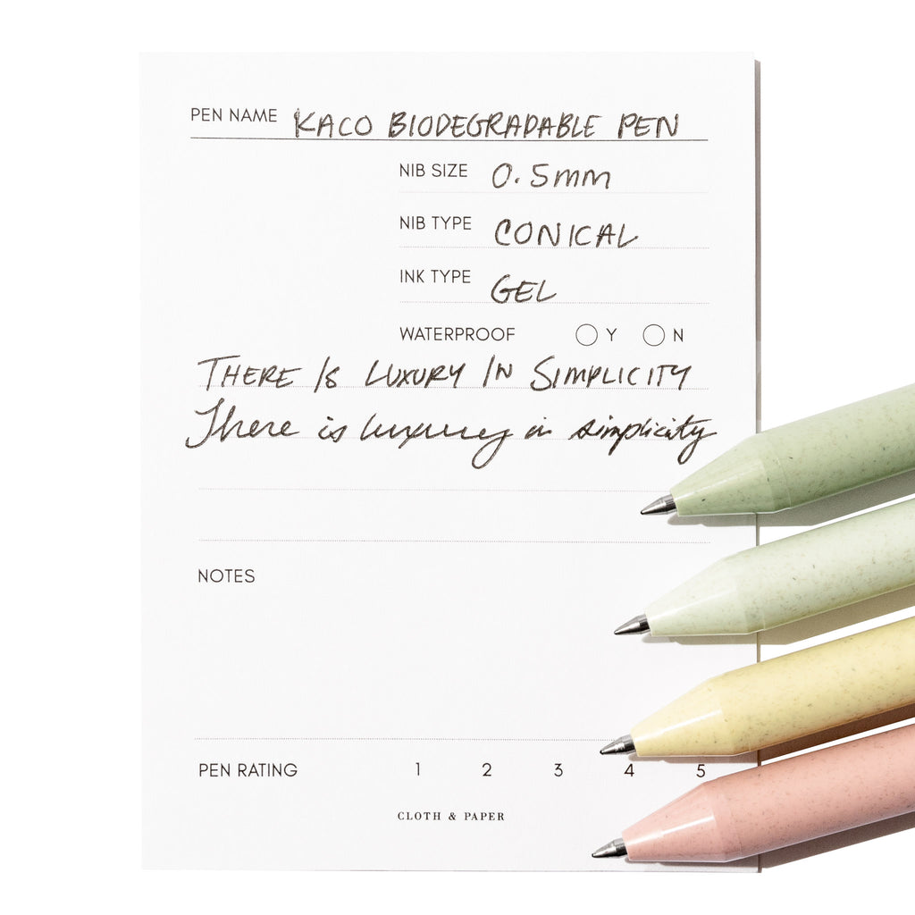 Four pens - green, blue, yellow, and red - rest on an in use pen testing sheet.