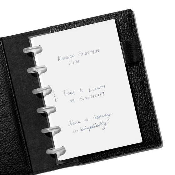 Writing sample displayed inside a black leather folio on a neutral background.