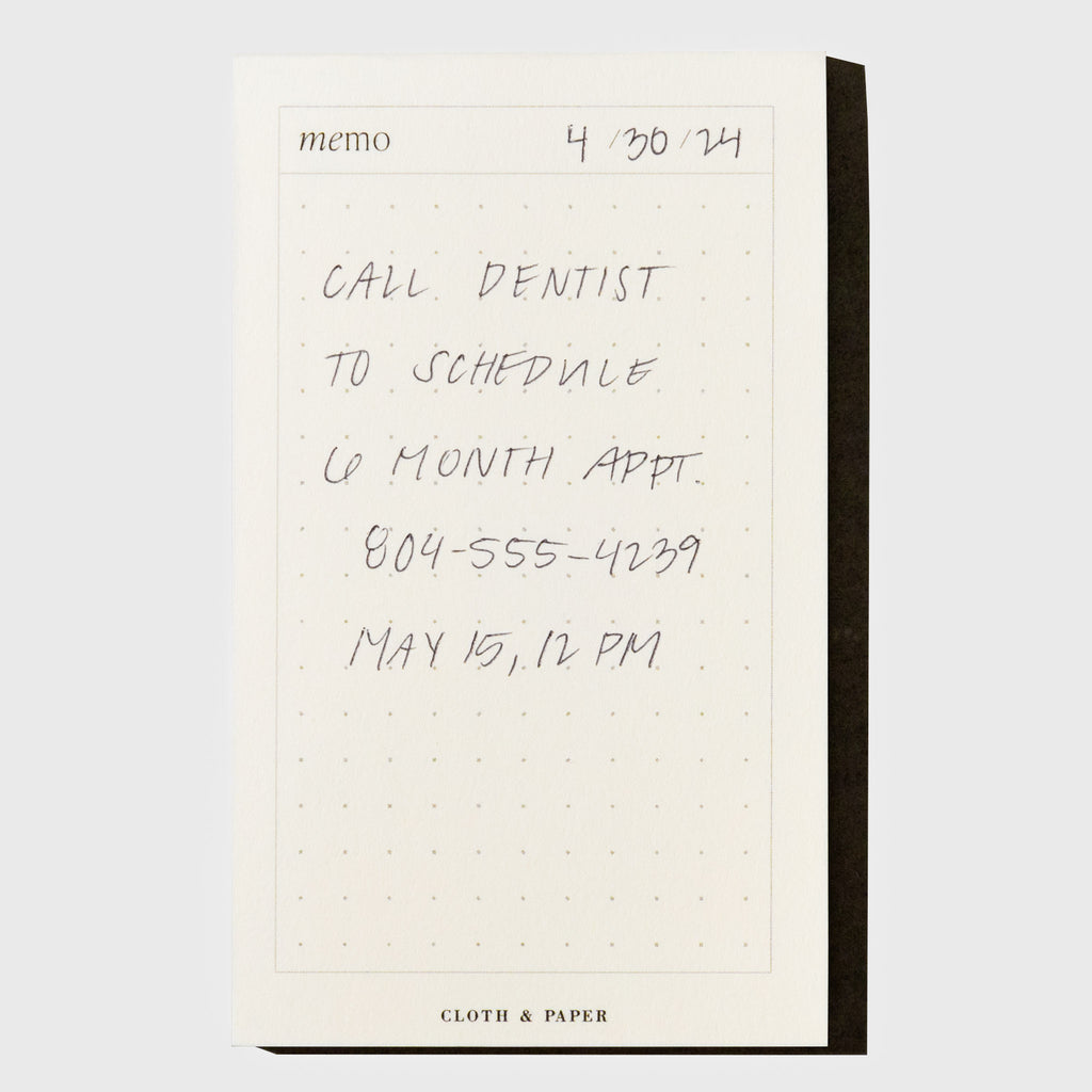 Notepad shown on a neutral background. A note is written on it, reading as follows: "4/30/24 / Call dentist to schedule 6 month appointment. 804-555-4239 / May 15, 12 PM"