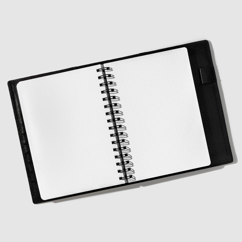 Notebook in use inside a leather folio. Notebook displayed on a white background. Color pictured is Avant Garde.
