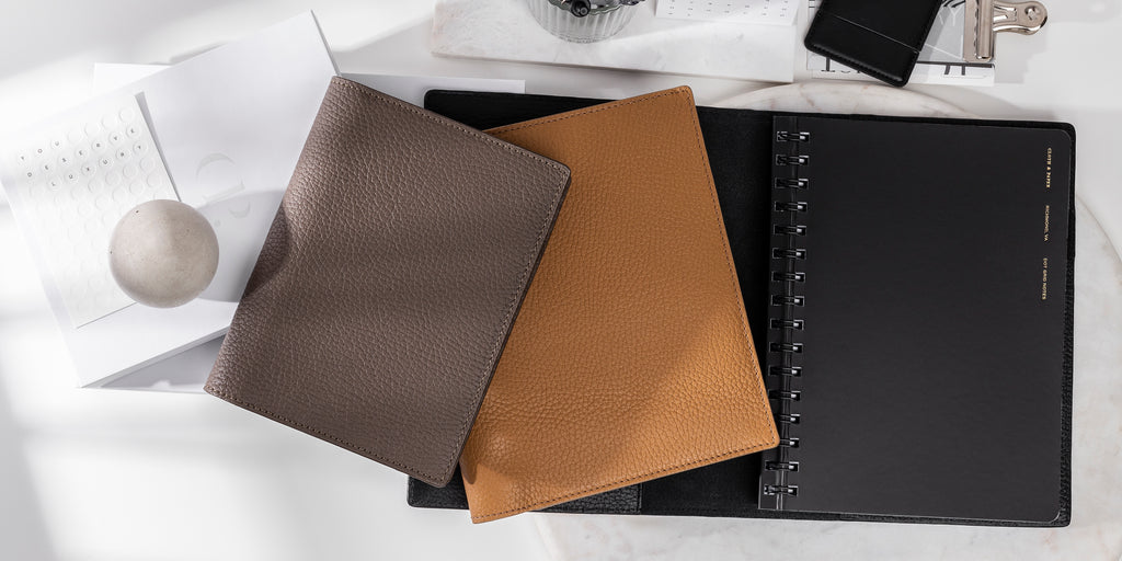Heirloom Leather Folios with a Black Espana Notebook on a white desk with accessories