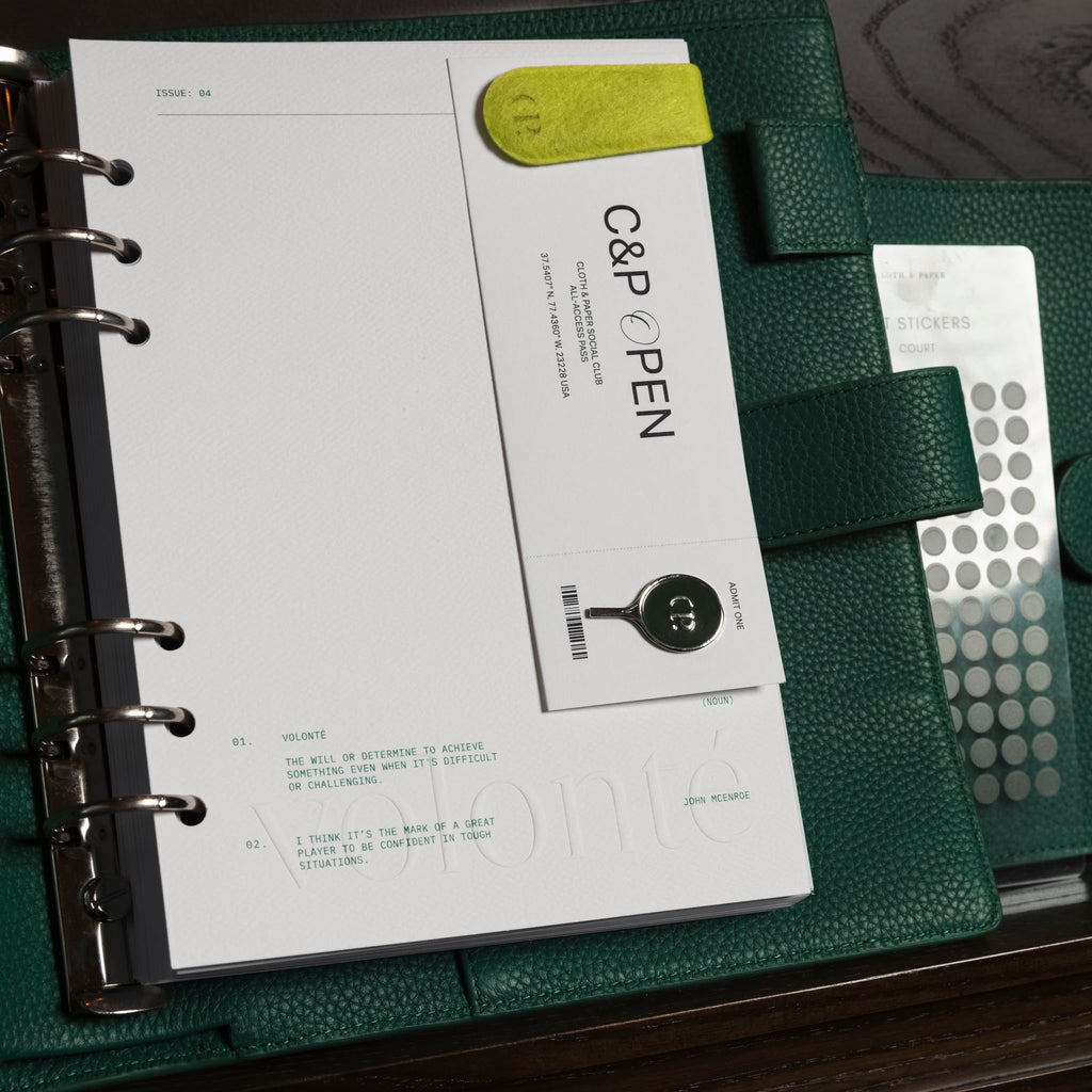 Dashboard shown inside a green leather agenda. It is decorated with a Cloth and Paperclip, enamel pin, and stickers.