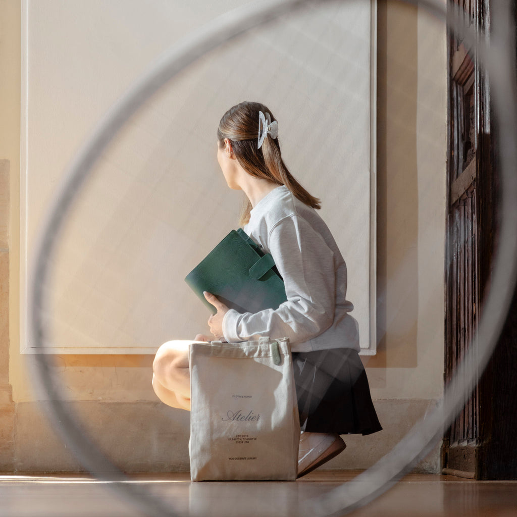 A female model holds an A5 agenda, crouching on the floor. She is framed by a tennis racket, which is out of focus and accentuating her pose.