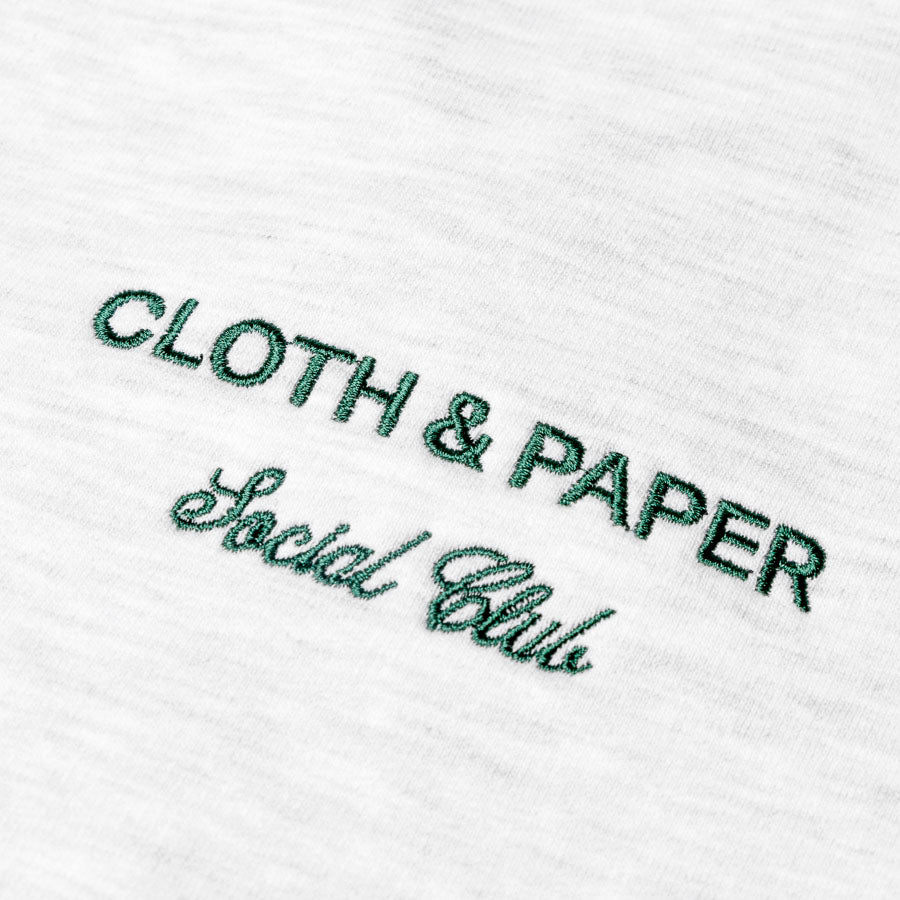 Closeup of green embroidery on the shirt. Text reads "CLOTH & PAPER | Social Club"