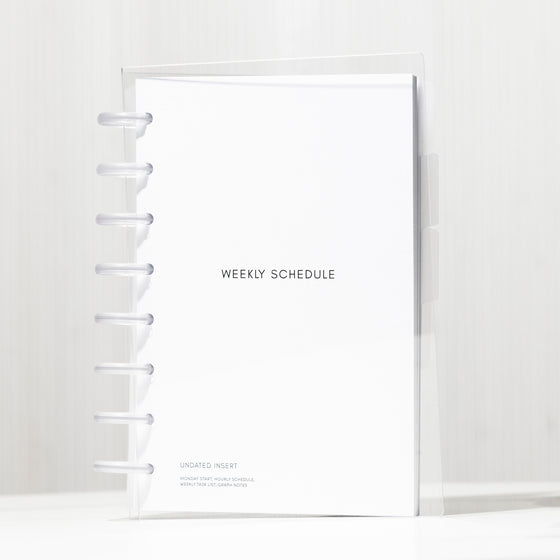 Half letter-sized Beginner Planner Bundle enclosed in a clear vinyl cover, resting on a white table with subtle shadows. 