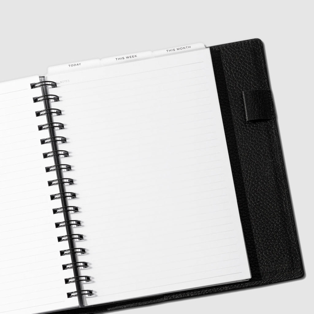 A5 Spiral Black Foil Cadence Tab Dividers displayed in a black leather planner.