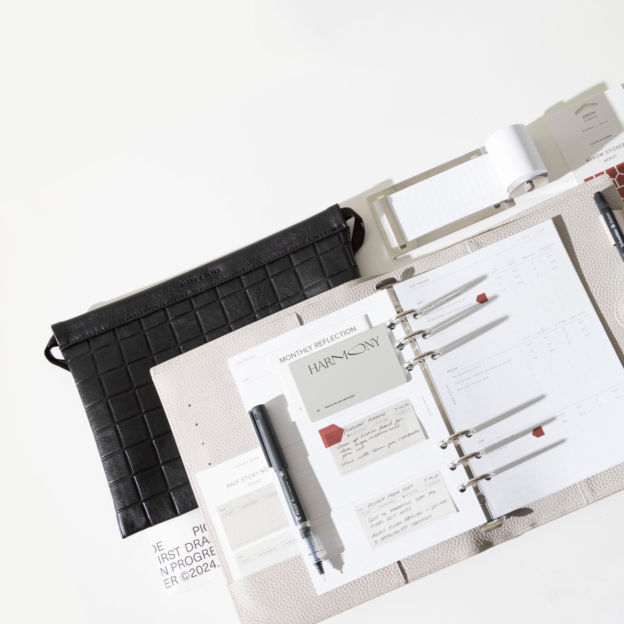 A 6-Ring Leather Agenda is opened and contains some items from the September Intention Box including Kanban Task Tracker Insert, Monthly Reflection Card, and Project Half Sticky Notes.  Also featured in image is Checkered Dust Bag and Task Roller.