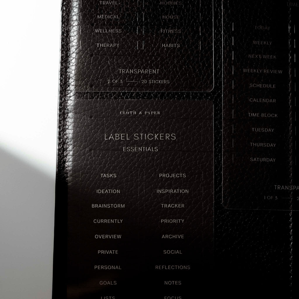 Close up image of the Clear Label Stickers against a black leather planner