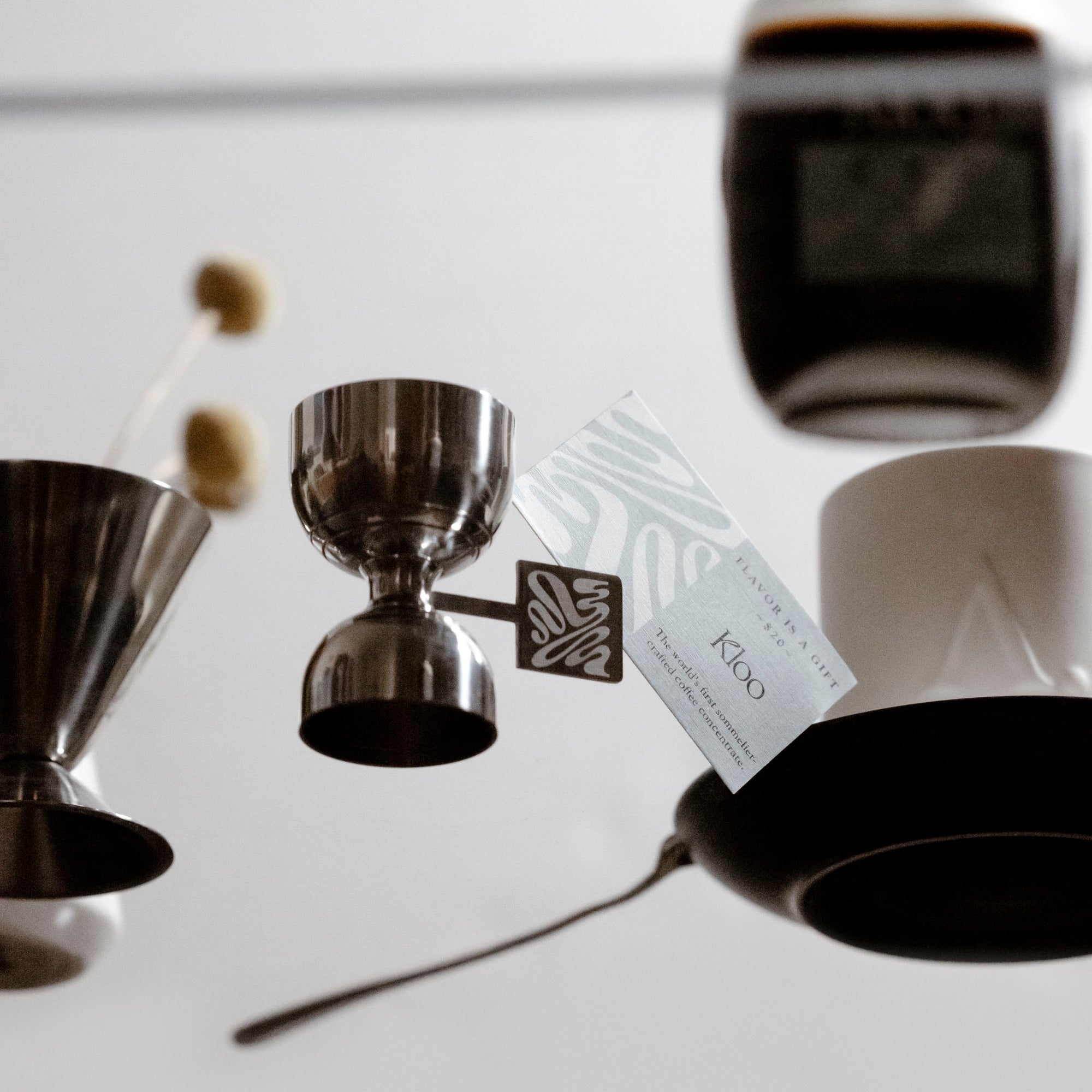 Some pieces of the Coffee Concentrate Kit from Kloo are sitting on a glass table.