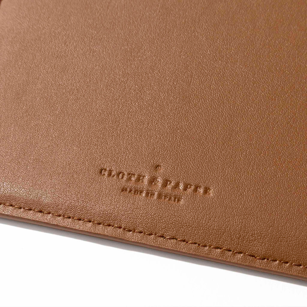 Closeup of clay brown folio's textured vegan leather and stamped Cloth and Paper logo.