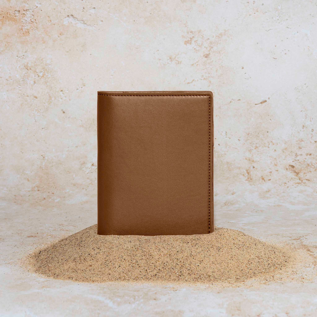 Cactus Vegan Leather Folio, CP Petite, Cloth and Paper. Folio displayed on a textured tan background, placed in a pile of sand. Color pictured is clay brown. 
