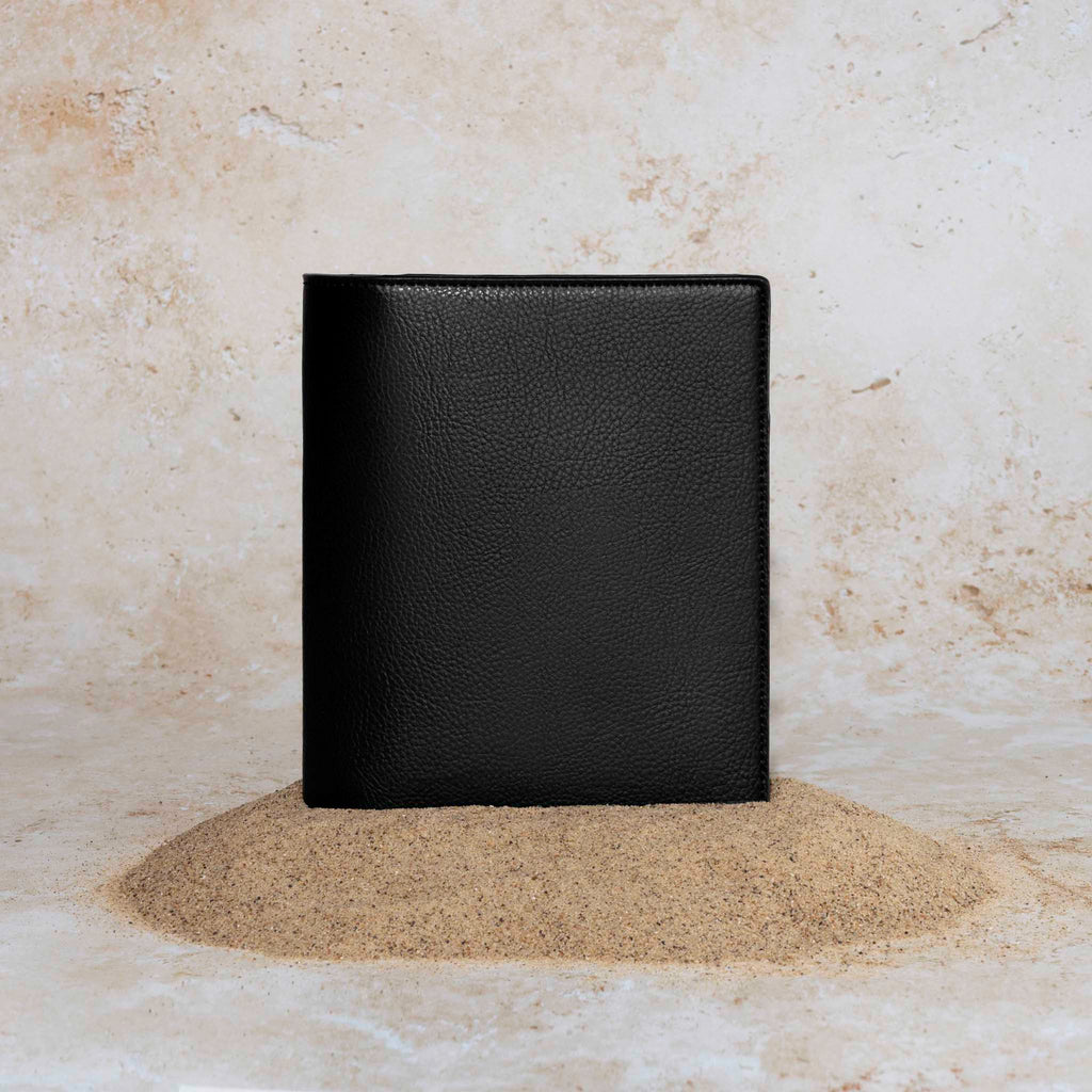 Cactus Vegan Leather Folio, HP Mini, Cloth and Paper. Folio displayed on a textured tan background, placed in a pile of sand. Color pictured is mesa black.