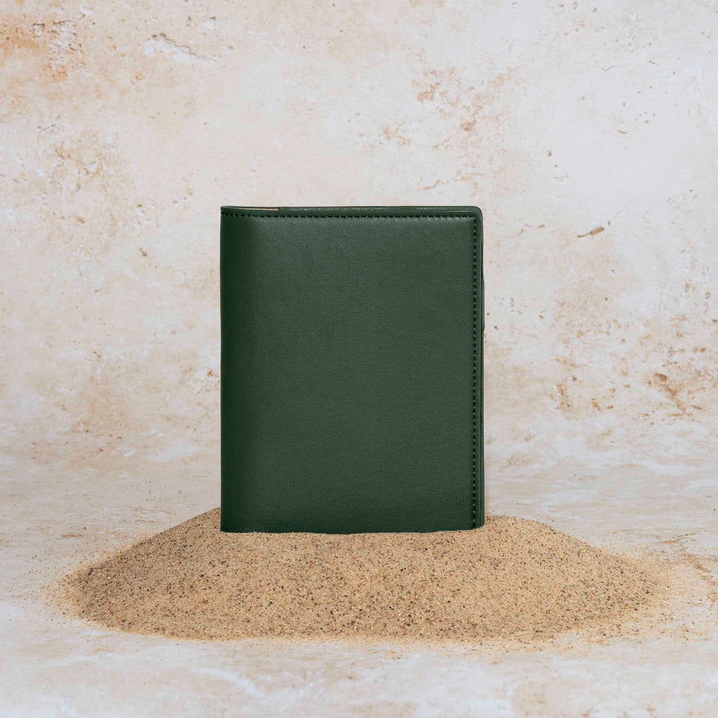 Folio displayed on a textured tan background, placed in a pile of sand. Color pictured is valley green. 