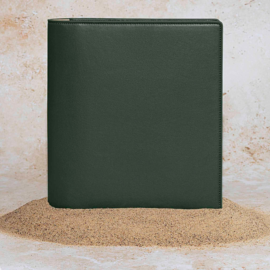 Folio displayed on a textured tan background, placed in a pile of sand. Color pictured is valley green. 