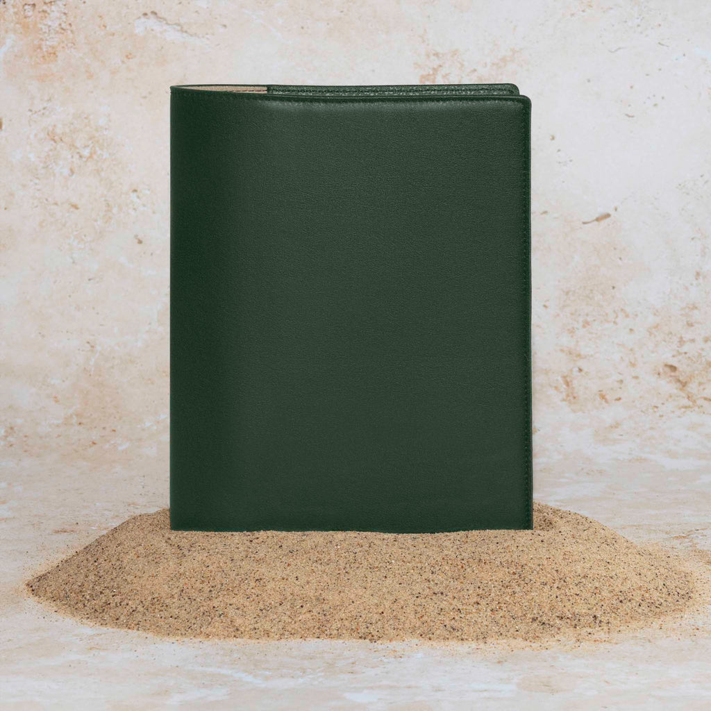 Folio displayed on a textured tan background, placed in a pile of sand. Color pictured is valley green.