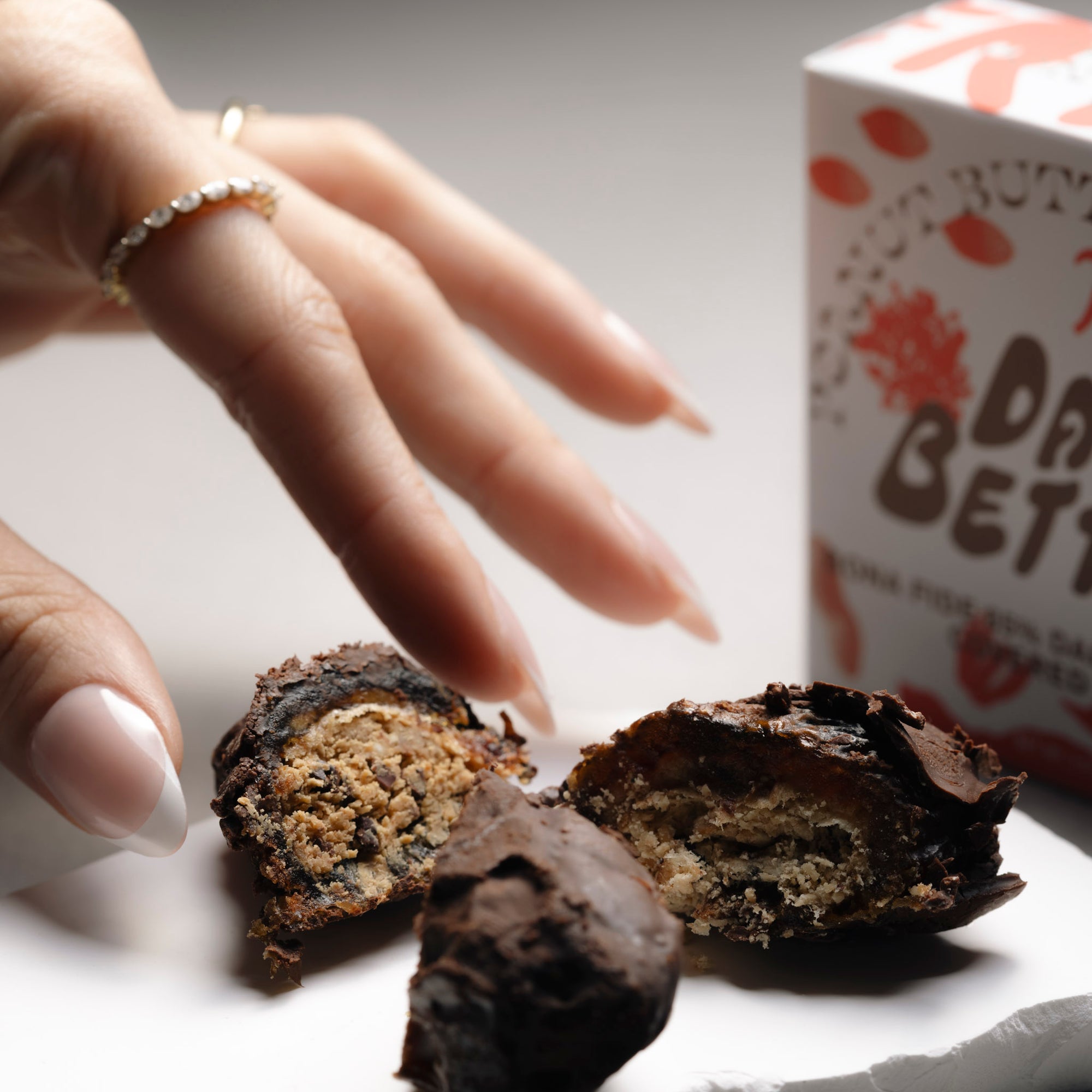 A hand is reaching for a Chocolate Covered Date.