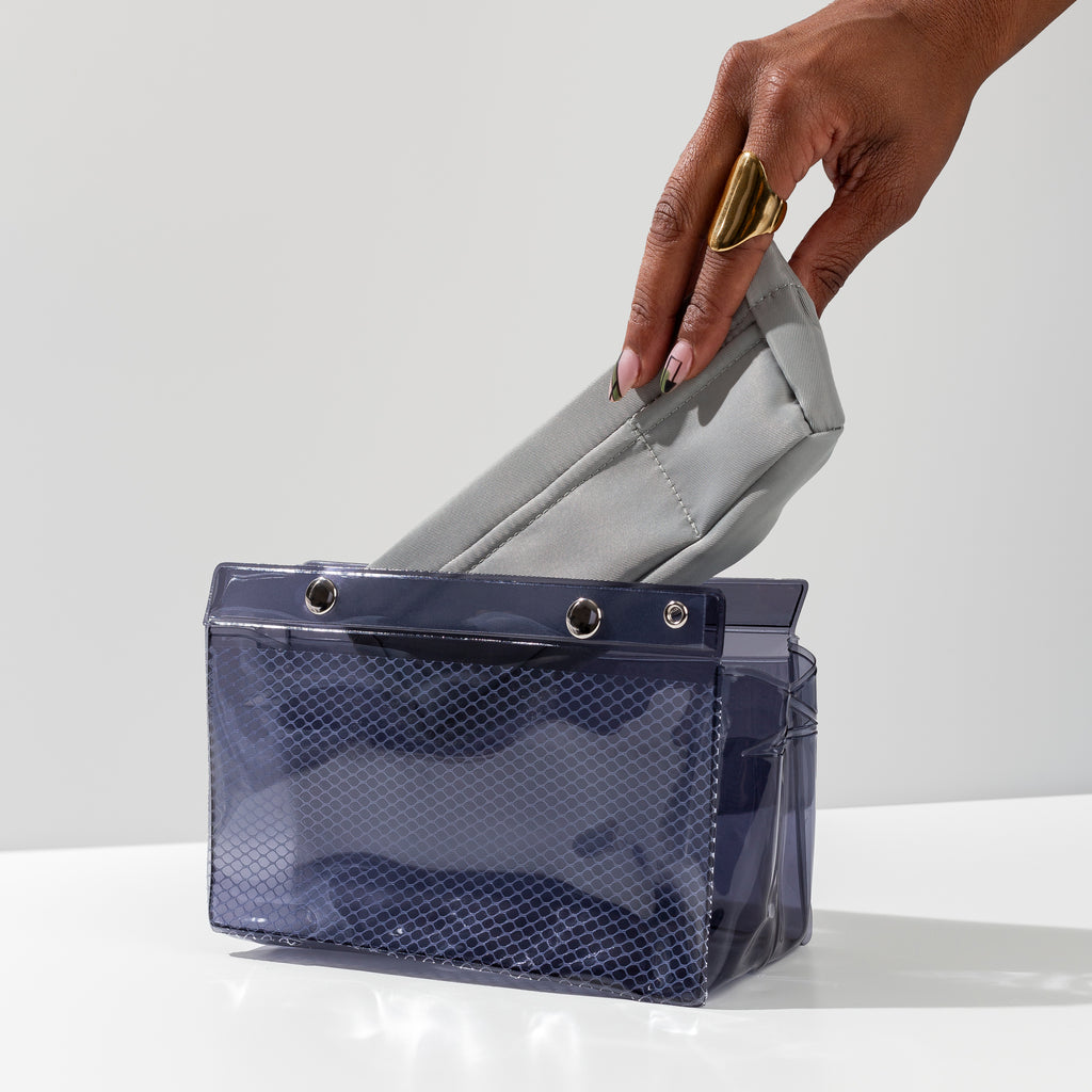 A hand is placing the Ristretto Liner inside the Double Carryall Pouch.