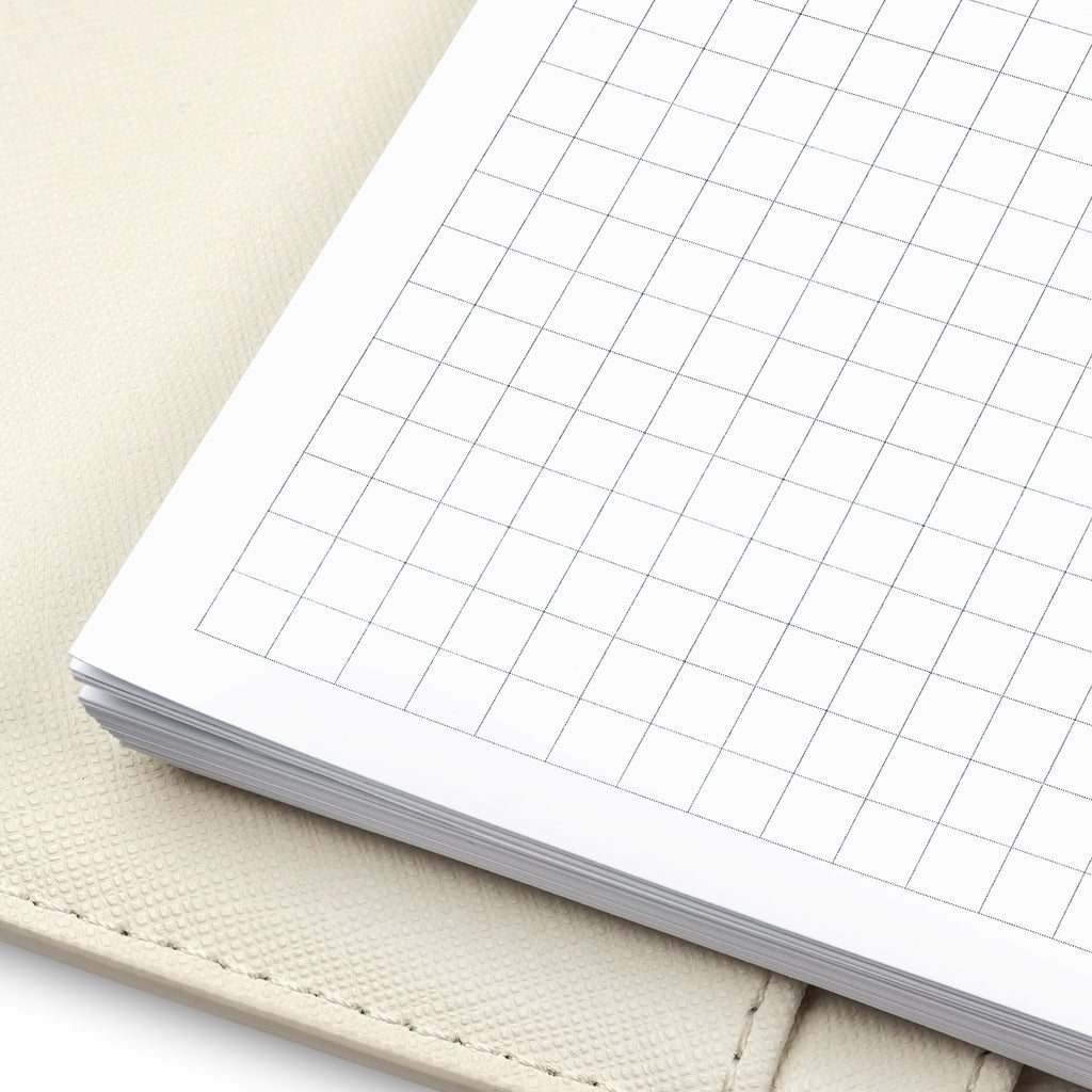 Close up of graph paper inserts in use inside a white leather agenda.