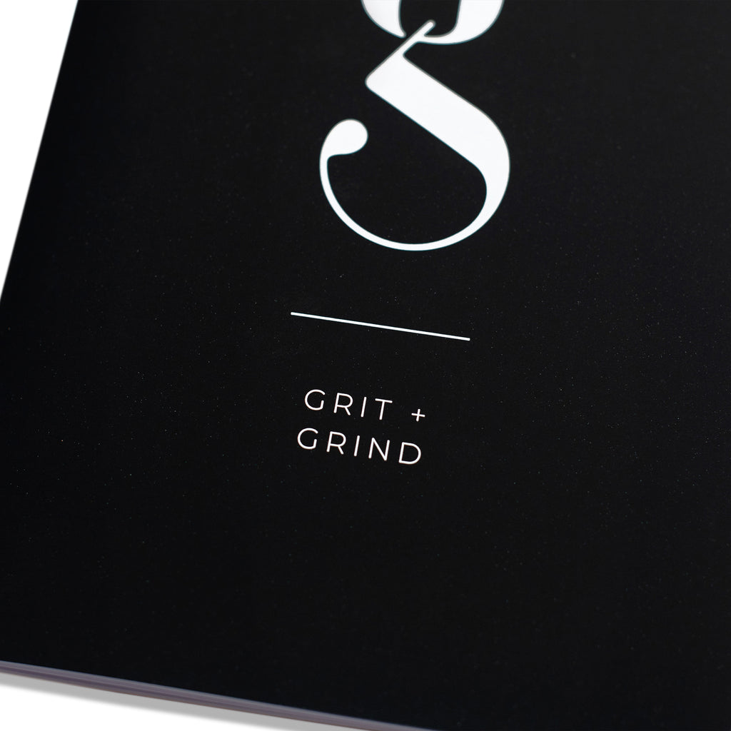 Closeup of text on notebook cover that reads "grit and grind."
