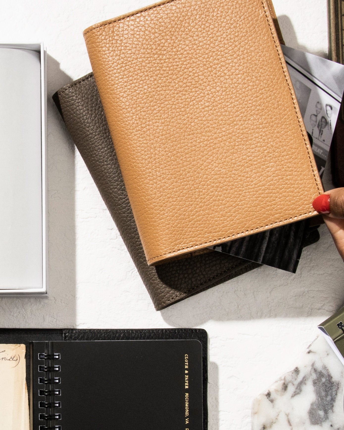 A couple Heirloom Folios are sitting on a marble table with other surrounding planner accessories.