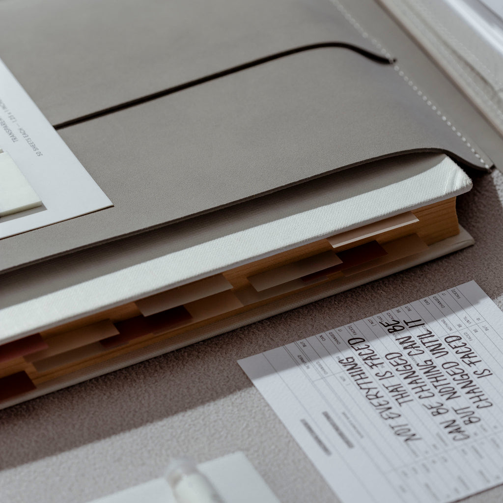 Book sleeve shown on a textured surface with a book stored inside of it.