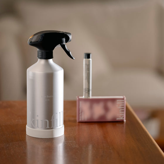 A bottle of Kinfill Cleaner and a brush placed on a table, ready for cleaning tasks.