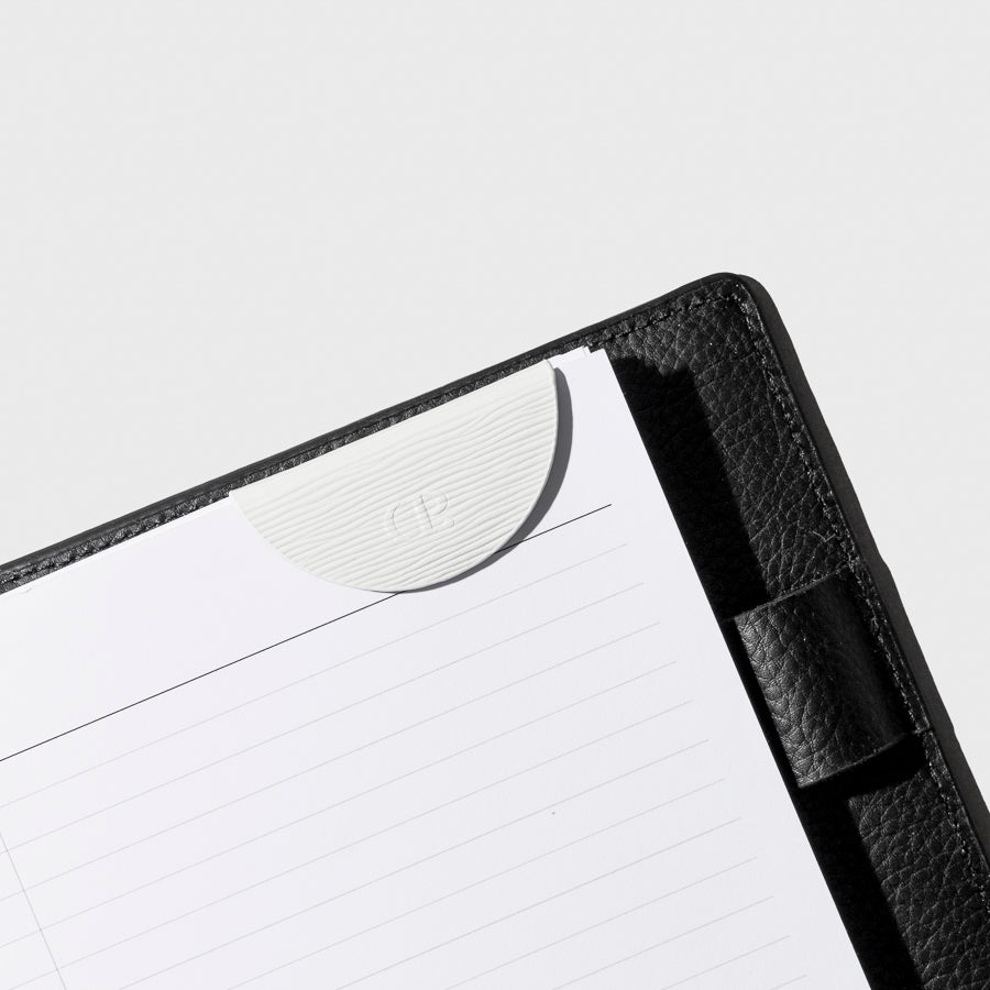 White bookmark in use inside a black leather agenda.