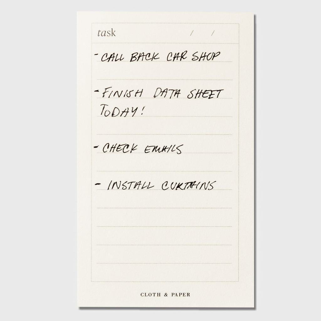 Notepad displayed on a neutral background. It is filled out with a task list that reads as follows: "Call back car shop / Finish data sheet today! / Check emails / Install curtains"