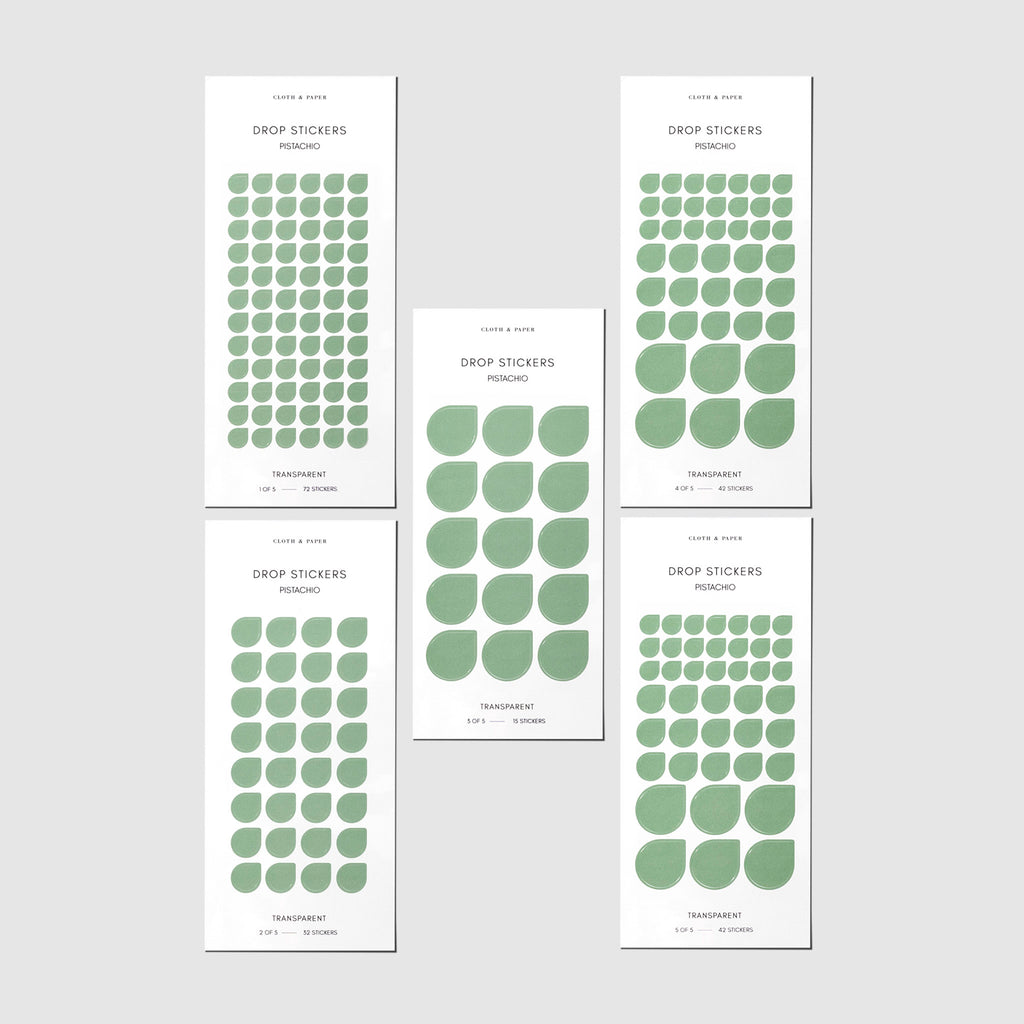 Minimal Shape Sticker Set, Transparent Drops, Pistachio, Cloth and Paper. Drop stickers in their packaging on a gray background.