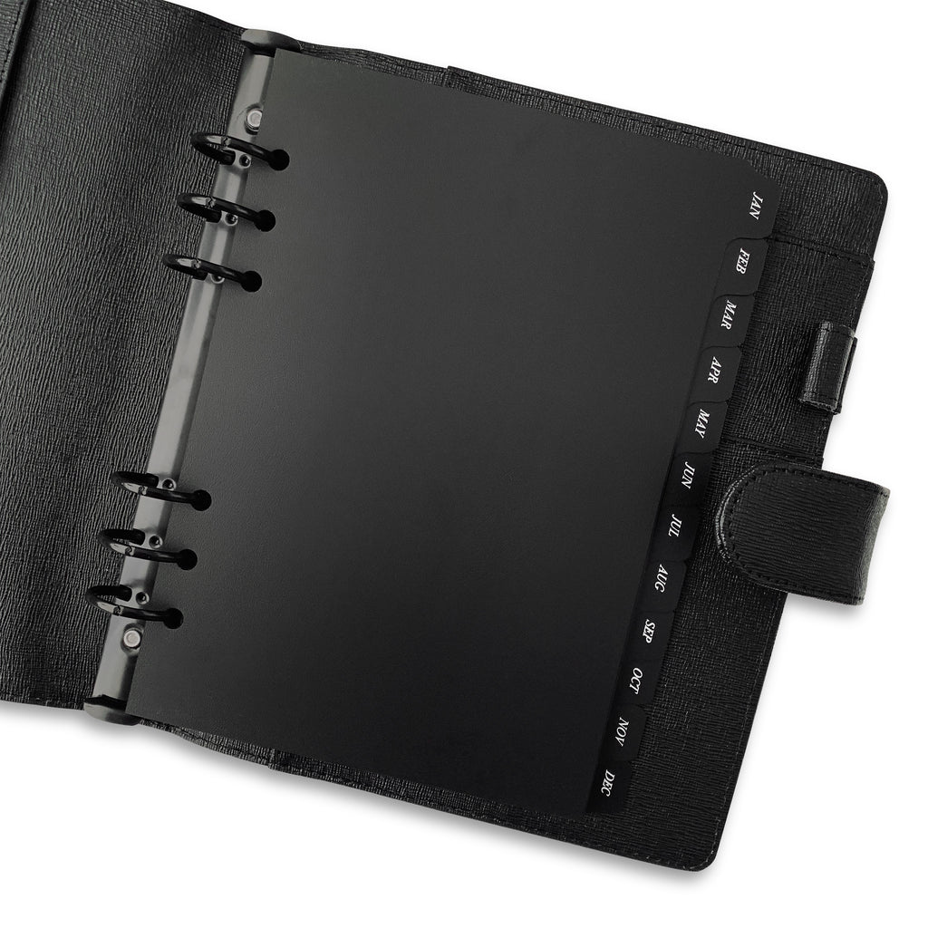 Monthly Side Tab Planner Dividers | Black Plastic | White Foil | Cloth and Paper. Dividers in use inside a black leather agenda.