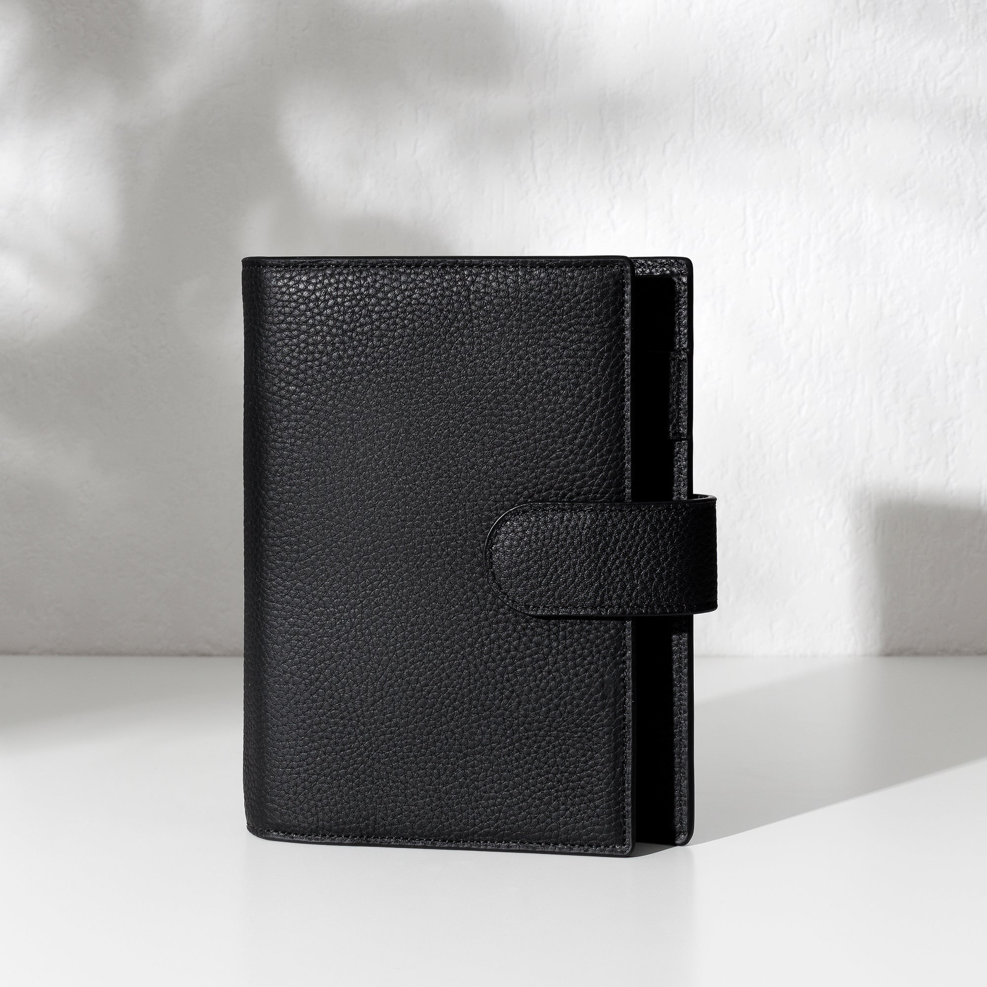 Black leather agenda displayed on an off-white background.