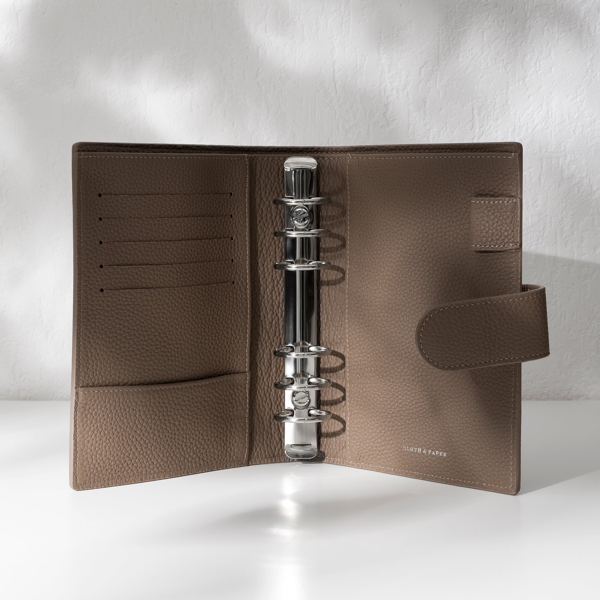 Cortado leather agenda displayed on an off-white background. It is opened to display the silver hardware and company foil stamp.