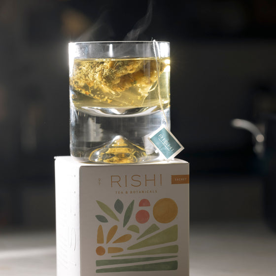 A glass of Rishi Tea rests elegantly atop a decorative box, showcasing a serene moment of tea enjoyment.