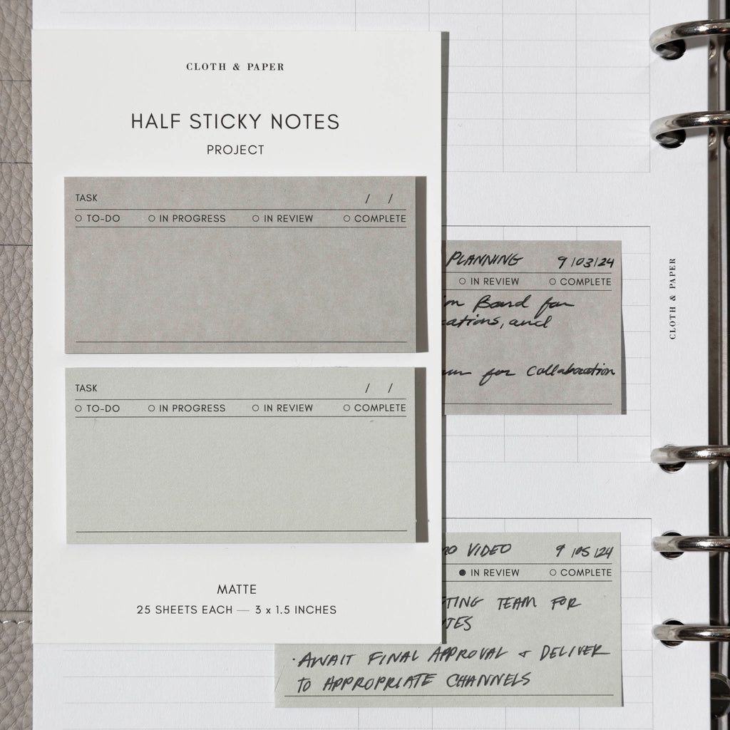 Sticky notes shown on their backing, placed on top of a planner insert with more in-use sticky notes.