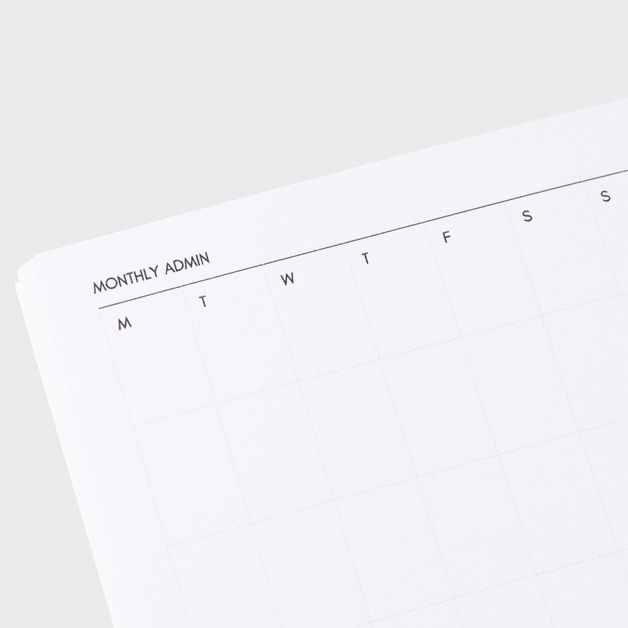 Close up image of the top left corner of the monthly admin notebook page. The page is turned on a left angle and is displayed on a light gray background