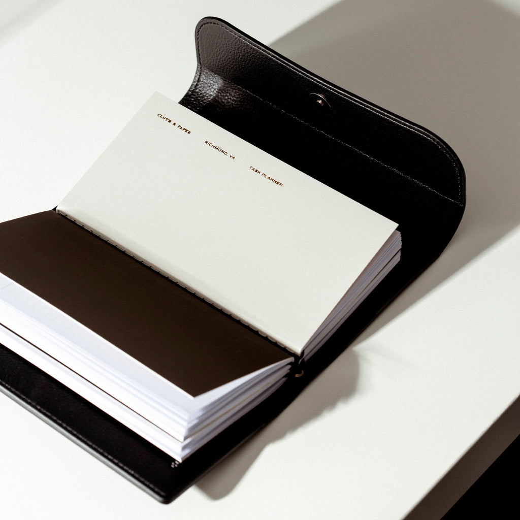 Traveler's Notebook Set with the cover open showing the notebooks inside, displayed on a white desk, casting a shadow