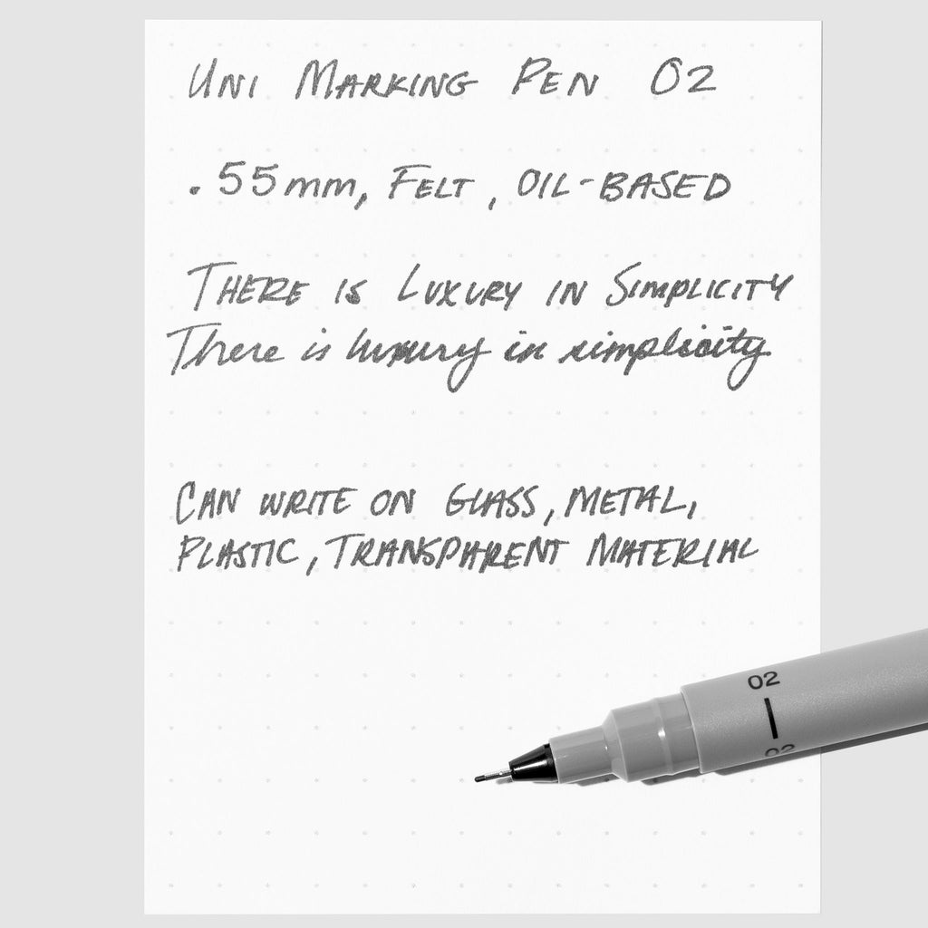 Uni Pin Marking Pen, 02, Cloth and Paper. Pen resting on paper displaying writing sample.