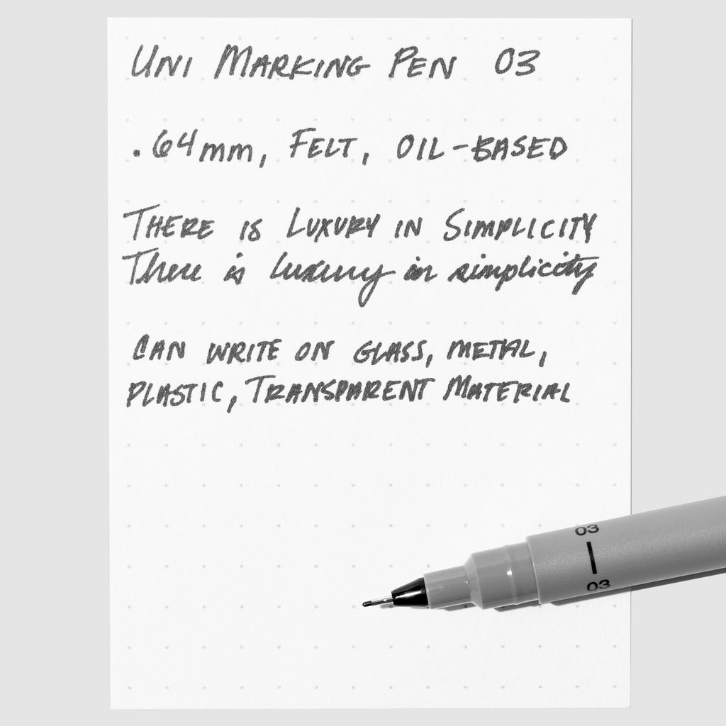 Uni Pin Marking Pen, 03, Cloth and Paper. Pen resting on paper displaying writing sample.