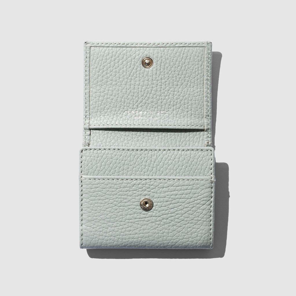 Leather wallet opened on a neutral background. Three internal pockets are visible.