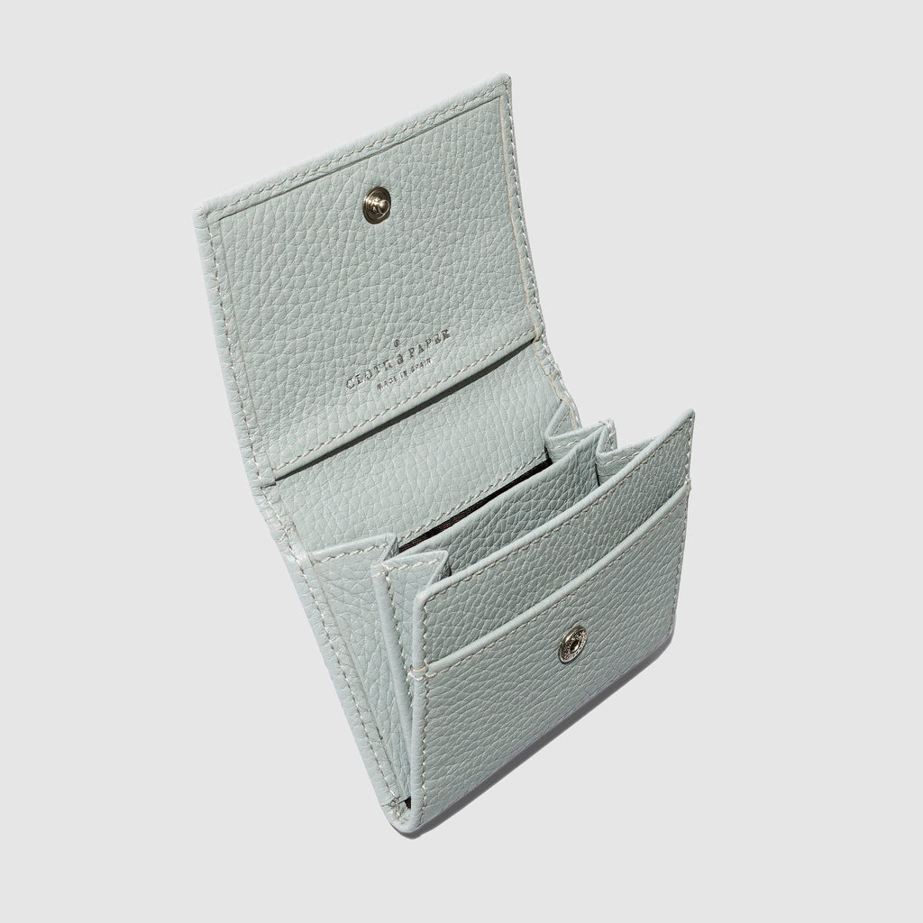 Leather wallet opened on a neutral background. Four internal pockets are visible.