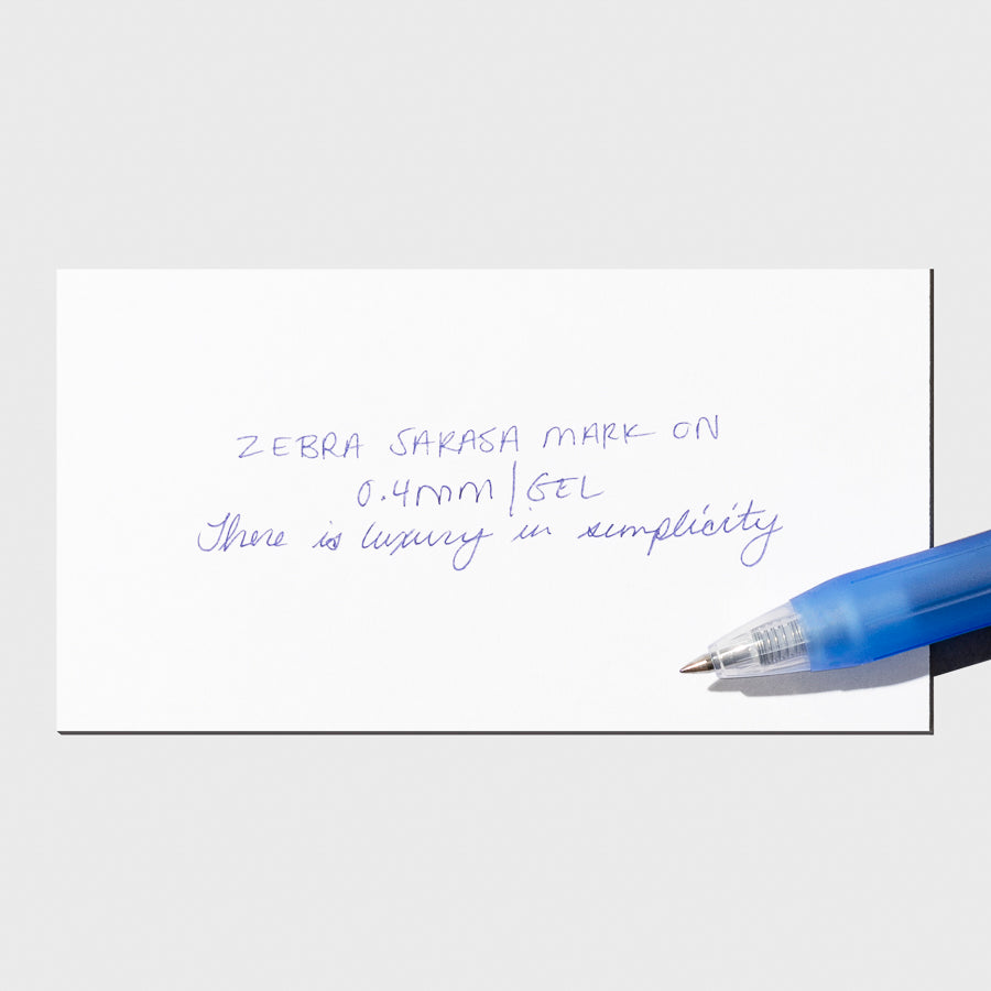 Pen in Blue resting on a pen test sheet displaying a writing sample detailing the pen's specs.